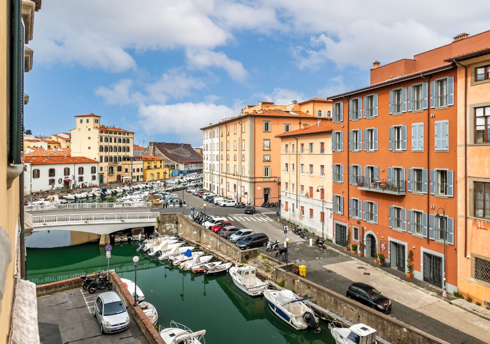The canal in Venezia Nuova, Livorno, with moored boats, a white bridge and orange buildings